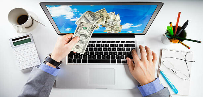 What Is The Best Way To Make Extra Money Online image 1 top view of desk with laptop with dollar bills coming out of it make xtra money online