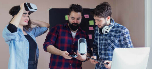 Learn How To Make Money In The Gaming Industry A Gamer's Guide image 10 people standing over computer discussing with vr headset testing make xtra money online