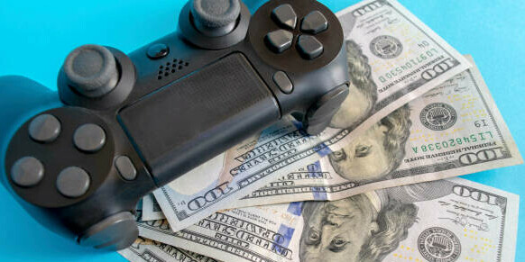 Learn How To Make Money In The Gaming Industry A Gamer's Guide image 6 playstation handset with dollar bills spread out make xtra money online